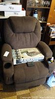 Front view of brown upholstered recliner chair with box placed on seat, branded Odyssey 50