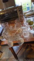 Pressed glass punch bowl with eight matching punch cups hanging around rim, plastic ladle included
