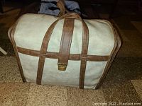 Beige and brown carry case for Singer Stylist sewing machine shown closed with top handles and metal buckle.