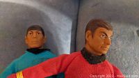 Close up image of two Star Trek figurines, one in red uniform, one in blue, showing facial details and uniform colors.