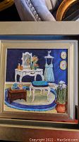 Framed country print showing a cozy room with vanity, stool, blue rug, flowers and dress on mannequin.