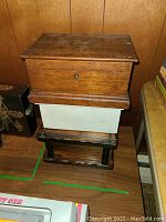 Photo showing stacked three wooden flip top storage boxes with visible wear, scratches, and keyhole on the largest box.