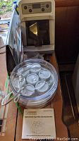 Wide view showing Euro Cuisine yogurt maker, Phillips pasta maker, jars with lids, and instruction manual.