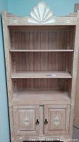 Full view of wooden Aztec style bookcase with two shelves and two-door cabinet below