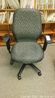 Front view of desk chair with patterned fabric upholstery and adjustable armrests in office environment.