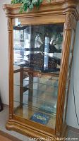 Full front view of the wooden curio display cabinet showing four glass shelves and sliding glass door.