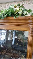 Photo of faux plants arranged on top of wooden cabinet showing green and variegated leaves