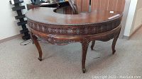 Full view of half moon writing desk showing curved top, three drawers, carved apron and legs