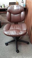 Full view of brown faux leather office chair with black wheeled base showing overall condition and design.