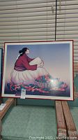 Photo showing RC Gorman print of a Native American woman with a basket of chillis, displayed indoors on wooden chair.