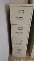 Front view of beige metal file cabinet with all four drawers closed.