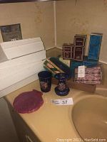 Overview of boxed perfumes, plastic trays and ceramic bathroom set on sink counter