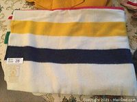 Folded blanket showing red, yellow and navy stripes on white wool