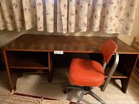 Wooden desk with open shelves on both sides and vintage metal office chair with orange vinyl seat and backrest