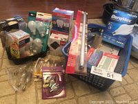 Overview showing various light bulbs in packaging and loose, including Sunbeam, Philips, and Sylvania brand bulbs in boxes and blister packs along with fluorescent tubes.