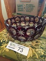 Side angle showing the deep red color and cut star and circle patterns on the crystal bowl with scalloped rim.