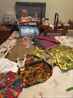 Wooden fold-out sewing box with assorted notions and buttons around it, along with various fabrics and patterns spread out on a white surface