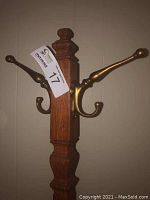 Close-up of the solid wood post with attached brass hooks, showing detail of material and craftsmanship.