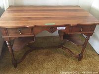 Front view of solid wood desk showing twin drawers, scalloped apron and turned legs