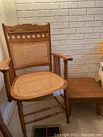 Solid wood armchair with carved wood backrest and woven wicker seat and backrest, situated next to a solid wood low-profile side table.