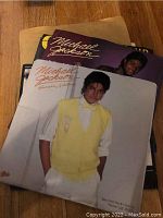 Photo showing two Michael Jackson vinyl record sleeves, one for 'Human Nature' featuring Michael in a yellow vest and bow tie.