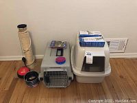 Shows the full set of items: the scratching post, pet carrier, litter box, collapsible bowls, and small bowls all arranged on the floor.