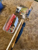 Full lot overview showing all items including dictionary, nativity scene figurines, sewing supplies, umbrella, walking cane and wooden musical instrument.