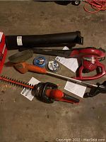 Overview photo of all included yard tools and accessories on floor, showing blower, trimmer, hedge trimmer, and trimmer line reels