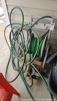 Overview of garden hoses, hose reel, and associated watering accessories on back patio.