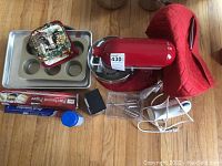 Overview of stand mixer, attachments, hand mixer, scale, bakeware, textile accessories and wrap boxes on floor