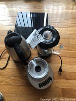 Electric kettle, blender, and digital bathroom scale on wooden floor viewed from above.