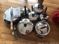 Top-down view showing multiple stainless steel pots with lids and handles, and the pressure cooker handles.