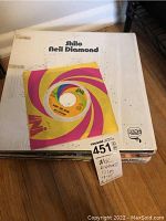 Stack of Neil Diamond vinyl records on a table with a visible album cover for "Shilo" and one 45 RPM single on top.