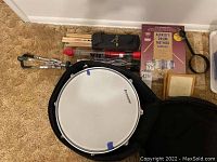 Overview of Ludwig snare drum with carrying case, brush set, drumsticks, practice pad, and drum method books arranged for display.
