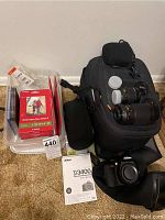 Black Nikon camera bag with two lenses, camera body, user's manual and software discs on carpet