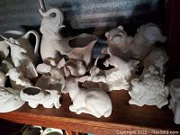 White ceramic animal and decorative figurines including elephant planter, bird, rabbit, frog all unpainted.