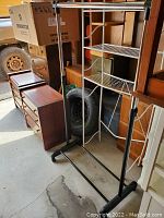 Photo of black metal coat and shoe rack with two wire shelves and horizontal hanging bar