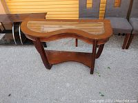 Curvy wooden couch table with glass top insert and lower wooden shelf, showing shape and wood grain finish