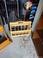 Wooden magazine holder placed on a concrete surface with furniture and art in the background