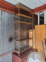 Photo of a tall metal shelving unit with five metal shelves, industrial style, located indoors against a wall.