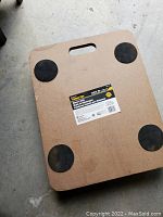 Top view of the flat wooden platform with four black rubber caster wheels attached at the corners, showing the user-friendly carry handle slot.