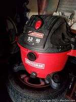 Photo of red and black Craftsman wet/dry vacuum cleaner with 5.0 peak horsepower and 45 liter capacity, mounted on a tire.