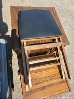 Top view of wooden folding chair showing black cushioned seat and wood grain frame.