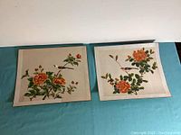 Two Asian silk prints of birds on flowering branches, fabric bordered, mounted on thick paper, approx 13x15 inches each