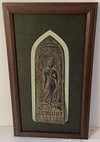 Frontal view of copper relief plaque mounted and framed, showing entire figure and background.