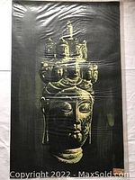 Photo of the full batik print artwork showing Buddha bust with multiple faces on its crown against a green background.