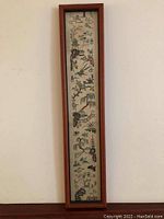 Full view of narrow vertical framed silk embroidery showing a continuous landscape scene with birds, trees, and architectural features.