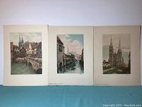 Three hand colored etchings displayed side by side featuring architectural and river scenes of Chartres, France by Albert Hubert.