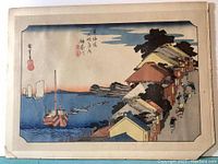 Full view of 'View of the Embankment' print showing boats and shoreline, mounted on board with chipped edges.