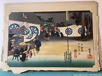 Full view of one mounted Hiroshige ukiyo-e print with visible edge chips and tears, depicting a night scene with people and lanterns